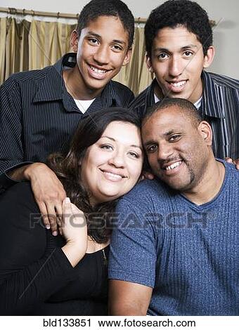 Stock Image - Parents and children smiling in living room. Fotosearch