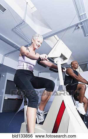 Stock Photograph - People using exercise machines in gym. Fotosearch