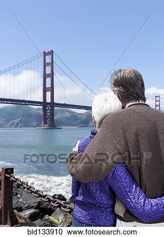 Stock Image - Senior Caucasian couple admiring Golden Gate Bridge, San Francisco, California, United States. Fotosearch