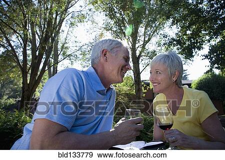 Stock Photo - Senior Caucasian couple drinking wine outdoors. Fotosearch