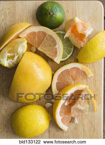 Stock Image - Sliced and squeezed fruit on wooden board. Fotosearch