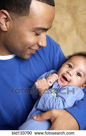 Stock Image - Smiling father holding baby. Fotosearch