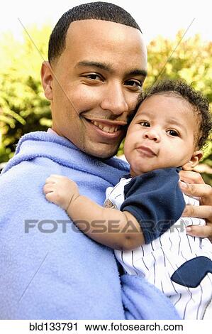 Stock Image - Smiling father holding baby. Fotosearch