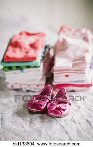 Picture - Stack of baby clothes with shoes. Fotosearch