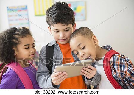 Stock Image - Students using digital tablet in classroom. Fotosearch