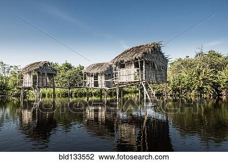 Stock Image - Thatch houses built over rural lake. Fotosearch