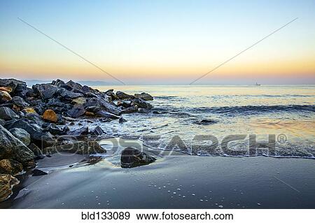 Stock Photo - Waves washing up on rocky beach. Fotosearch