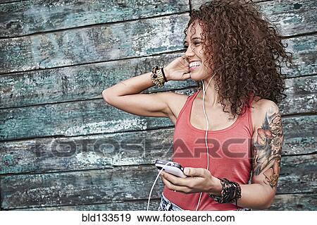 Woman listening to mp3 player on city street View Large Photo Image Stock Photo - Woman listening to mp3 player on city street. Fotosearch