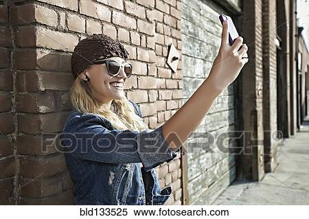 Stock Photography - Woman taking picture of herself on city street. Fotosearch
