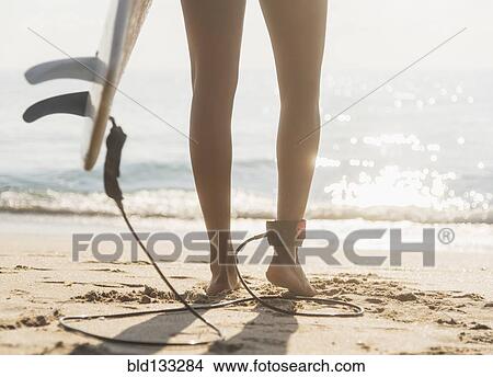 Picture - Woman tethered to surfboard on beach. Fotosearch