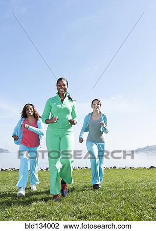 Stock Image - Women jogging by rural lake. Fotosearch