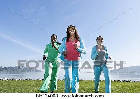 Stock Image - Women jogging by rural lake. Fotosearch