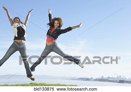 Stock Photography - Women jumping for joy on hilltop. Fotosearch