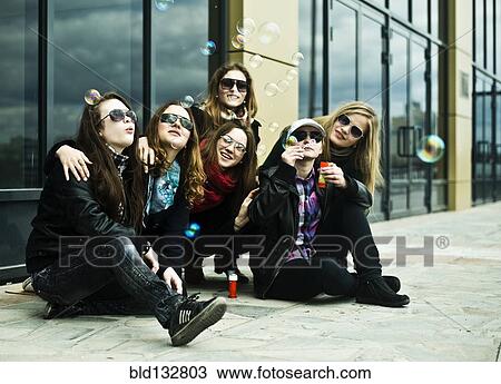 Stock Image - Women playing with bubbles on city street. Fotosearch