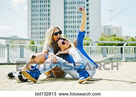 Stock Image - Women taking picture on city street. Fotosearch