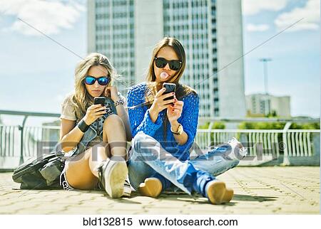 Stock Photography - Women using cell phones on city street. Fotosearch