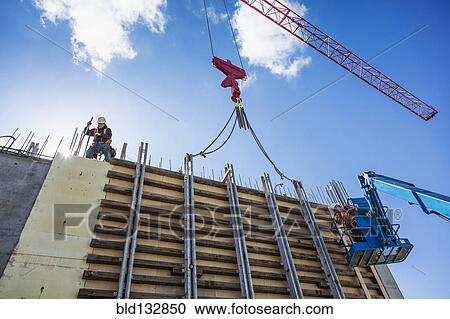 Stock Image - Workers on concrete wall form on construction site. Fotosearch