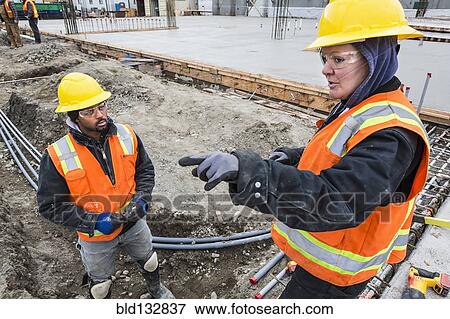 Stock Photo - Workers talking at construction site. Fotosearch