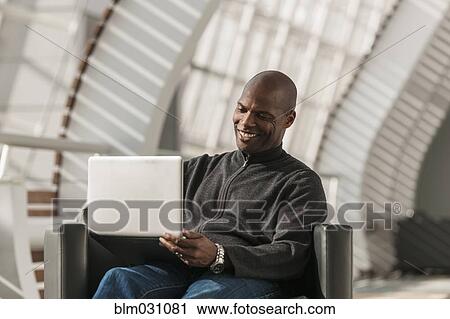 African American man using laptop in lobby View Large Photo Image Stock Image - African American man using laptop in lobby. Fotosearch