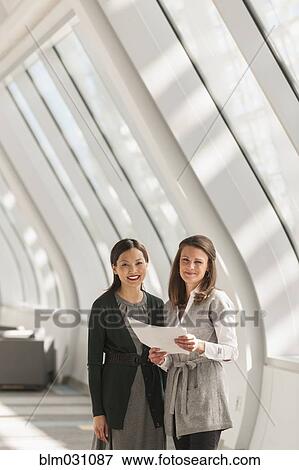 Businesswomen standing in lobby View Large Photo Image Stock Photo - Businesswomen standing in lobby. Fotosearch
