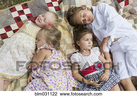 Stock Image - Caucasian children laying on blanket outdoors. Fotosearch