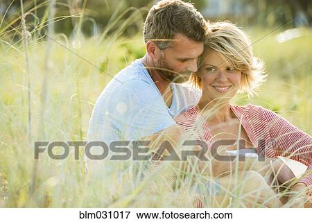 Stock Photo - Caucasian couple hugging in tall grass. Fotosearch