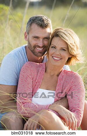 Stock Photo - Caucasian couple hugging in tall grass. Fotosearch