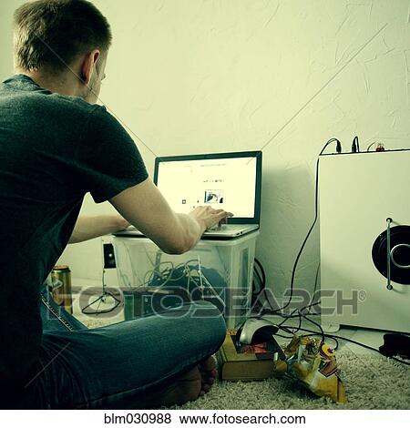 Stock Photo - Caucasian man using laptop on floor. Fotosearch