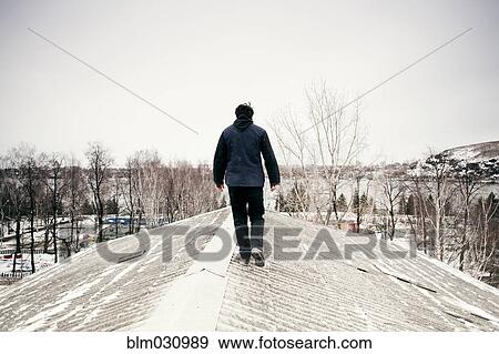 Caucasian man walking on snowy roof View Large Photo Image Stock Photo - Caucasian man walking on snowy roof. Fotosearch