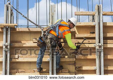 Caucasian worker hammering wood at construction site View Large Photo Image Stock Image - Caucasian worker hammering wood at construction site. Fotosearch