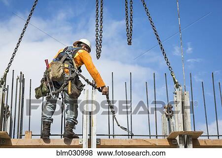Stock Photo - Caucasian worker holding chain at construction site. Fotosearch
