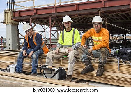 Stock Image - Caucasian workers smiling at construction site. Fotosearch