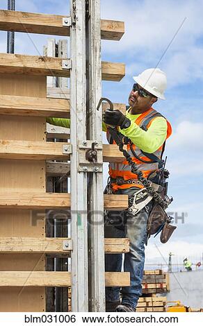 Hispanic worker holding hook at construction site View Large Photo Image Stock Photograph - Hispanic worker holding hook at construction site. Fotosearch