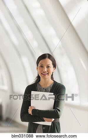 Stock Photo - Japanese businesswoman carrying papers in lobby. Fotosearch