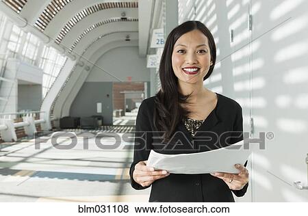 Stock Photo - Japanese businesswoman holding papers in office. Fotosearch