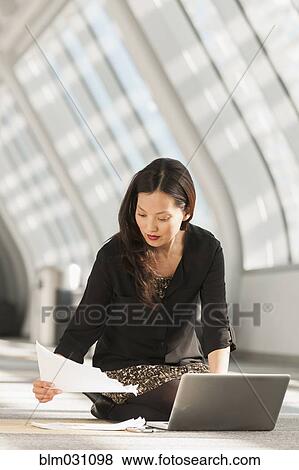 Stock Photo - Japanese businesswoman using laptop on lobby floor. Fotosearch