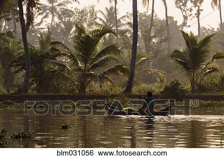 Stock Photograph - Man canoeing on tropical river. Fotosearch
