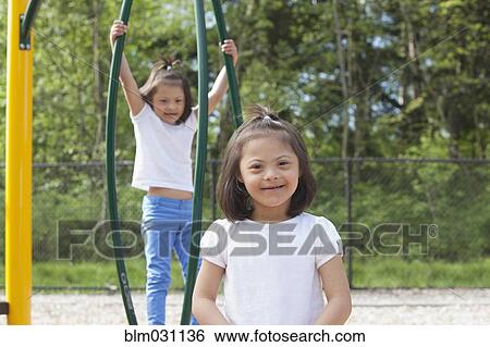 Mixed race Down syndrome girls smiling on playground View Large Photo Image Stock Photograph - Mixed race Down syndrome girls smiling on playground. Fotosearch