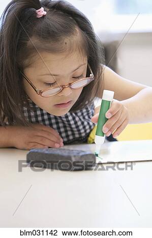 Stock Image - Mixed race Down syndrome student drawing in class. Fotosearch