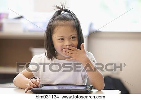 Mixed race Down syndrome student using tablet computer in classroom View Large Photo Image Picture - Mixed race Down syndrome student using tablet computer in classroom. Fotosearch