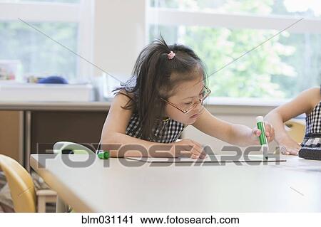 Stock Image - Mixed race Down syndrome students drawing in class. Fotosearch