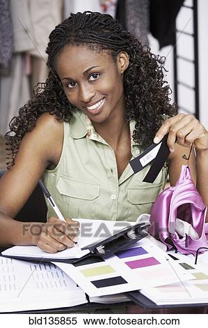 Stock Photography - African American dressmaker working in studio. Fotosearch