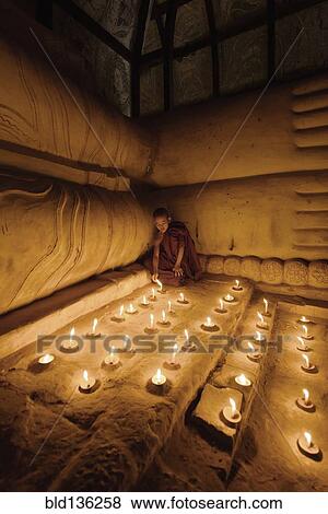 Stock Photo - Asian monk lighting candles in temple. Fotosearch
