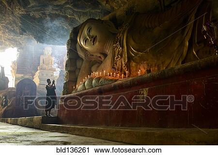 Stock Image - Asian monk lighting incense in temple. Fotosearch