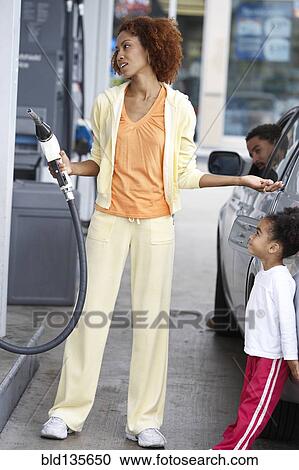 Black mother using pump at gas station View Large Photo Image Stock Image - Black mother using pump at gas station. Fotosearch
