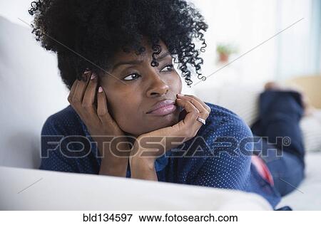 Stock Photo - Black woman laying on sofa. Fotosearch