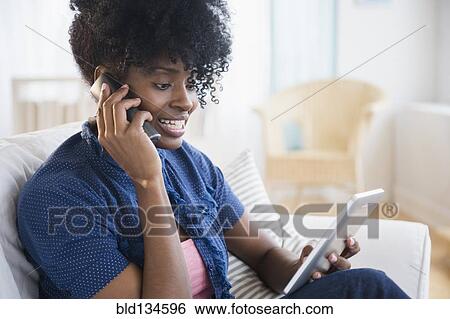 Black woman on phone using tablet computer View Large Photo Image Stock Photograph - Black woman on phone using tablet computer. Fotosearch