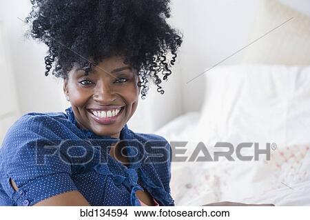 Picture - Black woman smiling on bed. Fotosearch