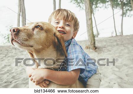 Boy hugging dog on wooded beach View Large Photo Image Stock Photograph - Boy hugging dog on wooded beach. Fotosearch