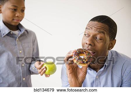 Stock Photo - Boy offering father healthy snack. Fotosearch